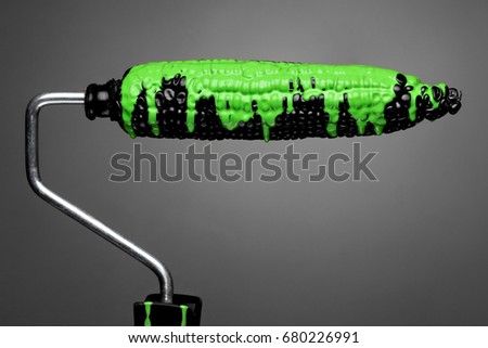 Paint Roller black corn with pouring green toxic paint on gray background. Fashion food concept.Creative advertising of paint.