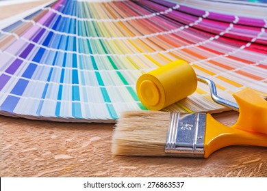 Paint Roller Brush And Pantone Color Palette Guide On Wooden Board Close Up View 