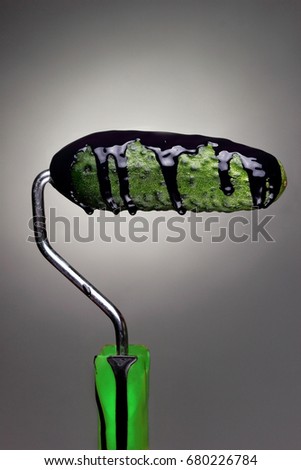 Paint Roller cucumber with pouring black paint on gray background. Fashion food concept.Creative advertising of paint