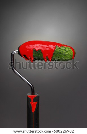 Paint Roller cucumber with pouring red paint on gray background. Fashion food concept.Creative advertising of paint