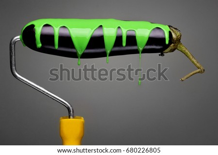 Paint Roller eggplant with pouring toxic green paint on gray background. Fashion food concept.Creative advertising of paint