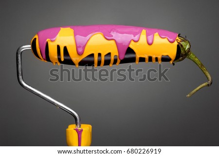 Paint Roller eggplant with pouring yellow and purple paint on gray background. Fashion food concept.Creative advertising of paint