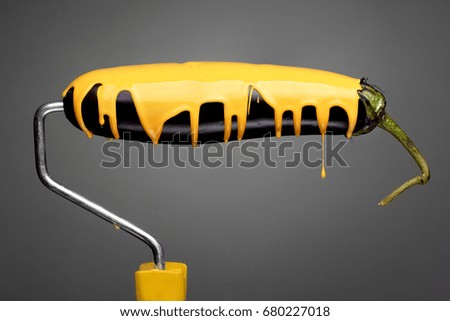 Paint Roller eggplant with pouring yellow paint on gray background. Fashion food concept.Creative advertising of paint