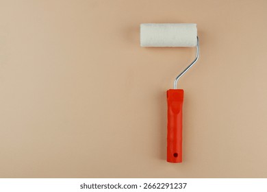 Paint roller with red handle on beige background for home decoration and DIY painting concept