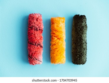 Paint rollers side by side in a row isolated on a blue background