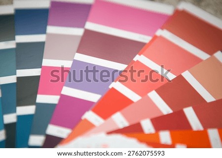 Paint sample fan deck with pink, purple, and blue swatches, color selection for interior walls, renovation design consultation, modern decor.