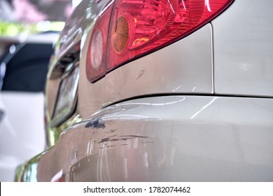 Paint Scratches On Car Bumper With Paint Damage From Car Crash. Close Up Of Car Dent And Paint Cracked & Peeling. Car Accident & Insurance Claim Concept. Paint Repair Garage Background.