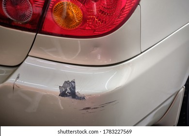 Paint scratches on car bumper with paint damage from car crash. Close up of car dent and paint cracked & peeling. Car accident & insurance claim concept. Paint repair garage background.