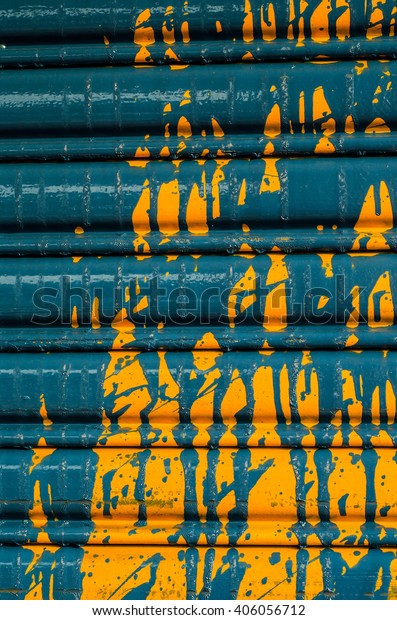 Paint splattered on\
the rolling shutter door of a car service workshop / Abstract\
background / The original color was yellow and blue the rest are\
colorized to get the\
effect