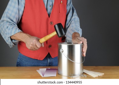 Paint Store Employee Pounding Down The Lid Of A Paint Can. Horizontal Format, With Paint Chips, Opener And Stir Sticks On The Counter. Man Is Unrecognizable.