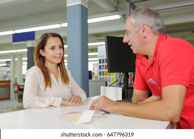 Paint Store Worker Talking To Customer Over The Counter