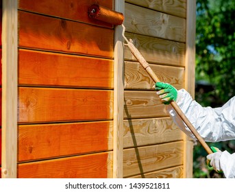 Paint wooden wall with roller brush in orange color by  painter in working clothes outdoors shot 
 - Powered by Shutterstock