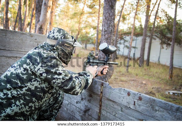 Paintball players in\
forest, hides and shooting. Man wearing protective\
equipment.Ukraine.Kyiv-november\
2015