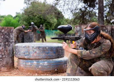 Paintball Players Of One Team In Camouflages And Masks Aiming With Gun In Shootout Playing Field