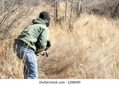 Paintball - Teen With Protective Mask And Paintball Gun In The Outdoors And In Search Of The Enemy