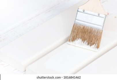 Paintbrush In Man's Hands Is Painting New Chair Boards