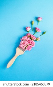 Paintbrush with pink roses on the blue background. Top view. Location vertical.