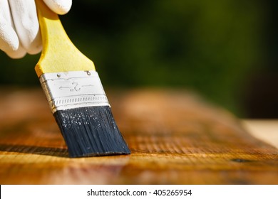 Paintbrush Sliding Over Wooden Surface, Protecting Wood For Exterior Influences, Weathering, Insects And Fungus. Carpentry, Woodwork, Home Improvement, Do-it-yourself Concept And Background. 
