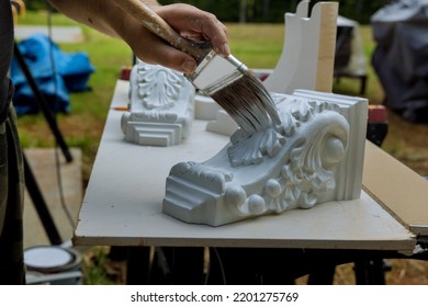 With A Paintbrush, Worker Paints Wooden Corbels For Kitchen Island On Table Surface