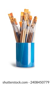 Paintbrushes in a blue plastic cup. Numerous used flat and round paintbrushes of various sizes, used by artists in one stroke painting. The bristles are made of natural and synthetic hairs. Photo.