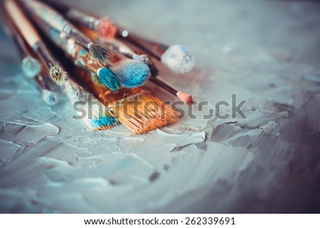 Paintbrushes on artist canvas covered  with oil paints