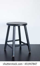 Painted Black Shabby Stool On Wooden Surface.