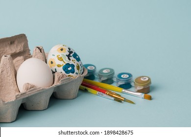 Painted Chicken Egg In Floral Pattern. DIY Craft For Easter Holidays With Kids. Botanical Decoration. Minimal Easter Egg On Blue Background. Craft For Spring Holidays