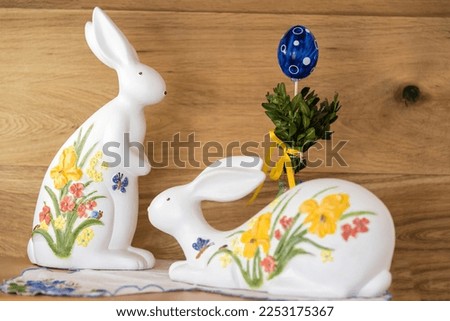 painted easter bunnies and easter egg as decoration in front of brown wooden wall