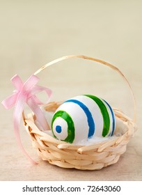 Painted easter egg in a basket with ribbon