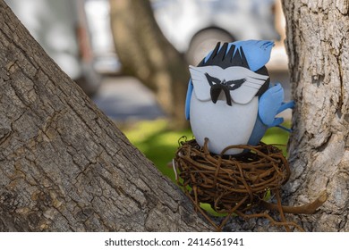 Painted easter egg of Blue jay in a  tree trunks. Cyanocitta cristata