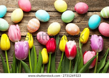 Painted Easter eggs and beautiful tulips on wooden table, flat lay