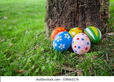 Ovos de Páscoa pintados escondidos na grama atrás de um tronco de árvore, pronto para a caça ao ovo de Páscoa jogo tradicional
