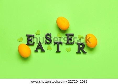 Painted eggs, word EASTER and hearts on green background