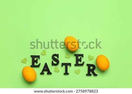 Painted eggs, word EASTER and hearts on green background