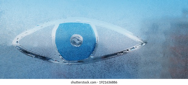 A painted eye on the misted spring glass of a plastic window
