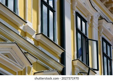 painted green wood windows. yellow stucco elevation. old classic architecture. white decorative elements. buildings and archiecture concept. travel and tourism. urban scene in Europe. bright sunlight