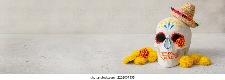 Painted human skull for Mexico's Day of the Dead (El Dia de Muertos), flowers and sombrero on light background with space for text - Shutterstock ID 2202037535