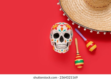 Painted human skull for Mexico's Day of the Dead (El Dia de Muertos) with sombrero and maracas on red background