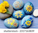 Painted round natural stones with decorative flowers.
