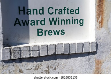 Painted Sign On Restaurant Exterior White Wall Advertising Hand Crafted Award Winning Brews In Green Lettering 