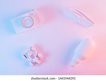 Painted White Camera; Eyeglass; Formula One Car And Light Bulb Against Pink Background