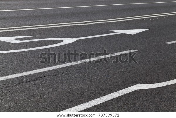 painted with white\
paint arrows on the road about going straight and turning to the\
left at the crossroads