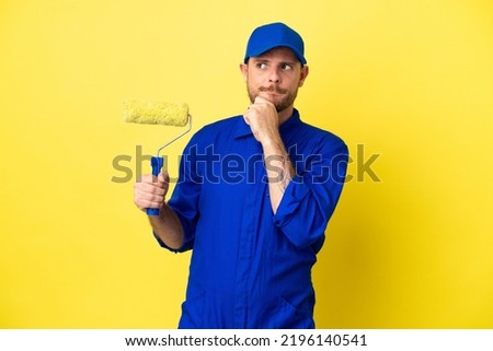 Painter Brazilian man isolated on yellow background having doubts and thinking