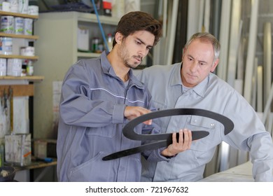 painter checking metal piece before painting