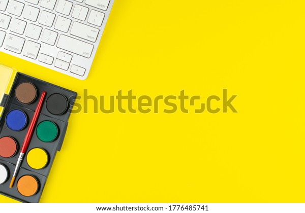 Painter colors palette\
and keyboard on yellow background. Top view with copy space.\
Workplace for painter.