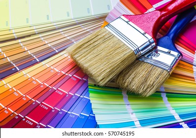 Painter and decorator work table with house project, color swatches, painting roller and paint brushes - Shutterstock ID 570745195