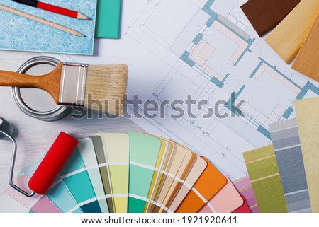 Painter and decorator work table with house project, color swatches, painting roller and brush, top view