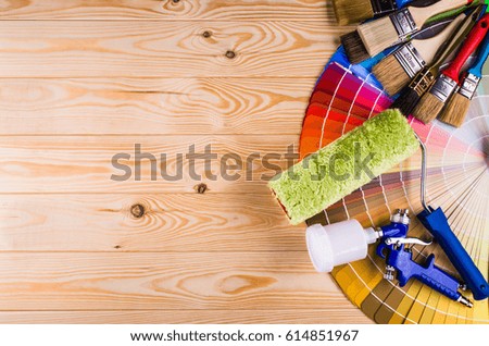 Painter and decorator work table with house project, color swatches, painting roller and paint brushes