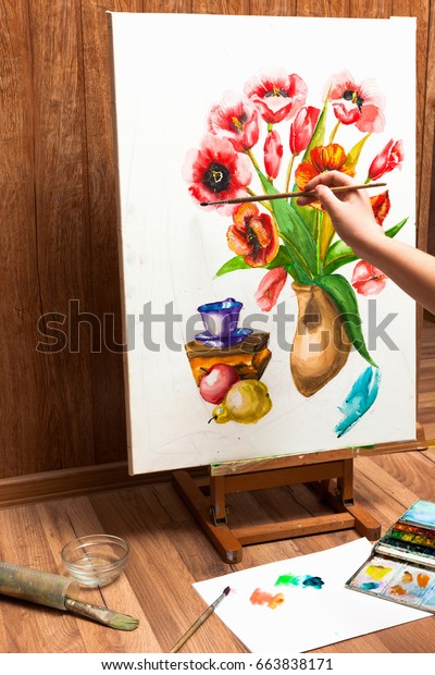 Painter drawing watercolor flowers.\
Unrecognizable artist\'s hand paints bouquet picture . Drawing\
lessons, art school, young artist\
concept
