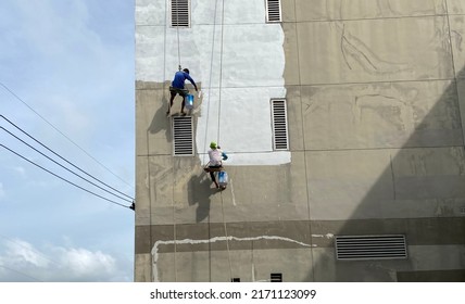 Painter Fixing The Wall And Painting On The Wall Of The Building Construction Worker With A Roller Brush Work On Tall Buildings Without Safety Equipment The Concept Of Dangerous Work At Heights